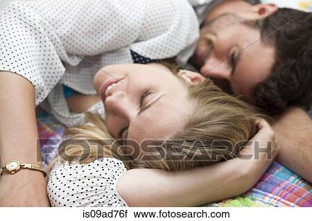 Stock Image - Close up of couple relaxing on bed. Fotosearch