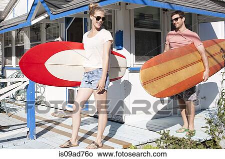 Couple on patio carrying surfboards, Breezy Point, Queens, New York, USA View Large Photo Image Picture - Couple on patio carrying surfboards, Breezy Point, Queens, New York, USA. Fotosearch