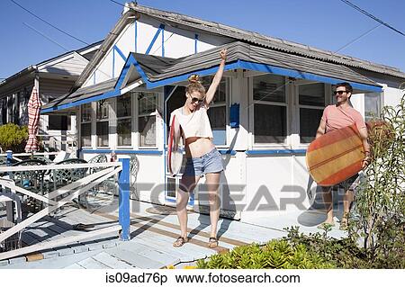 Stock Photography - Couple on patio with surfboards, Breezy Point, Queens, New York, USA. Fotosearch