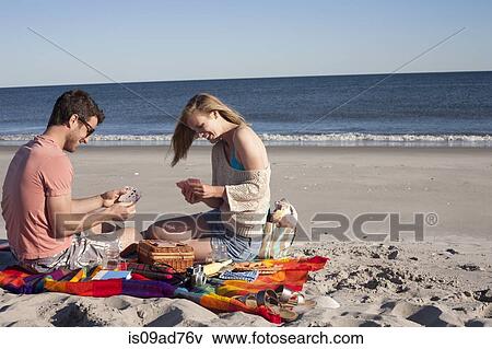 Stock Photo - Couple playing cards on beach, Breezy Point, Queens, New York, USA. Fotosearch