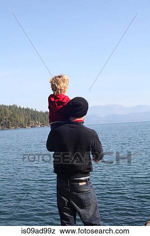 Stock Photo - Father and toddler daughter looking at view across lake. Fotosearch