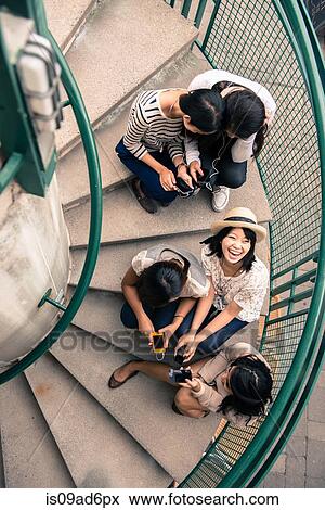 Five young women sitting on steps looking at smartphones View Large Photo Image Stock Photo - Five young women sitting on steps looking at smartphones. Fotosearch