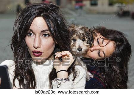 Friends holding pet dog for photograph View Large Photo Image Picture - Friends holding pet dog for photograph. Fotosearch
