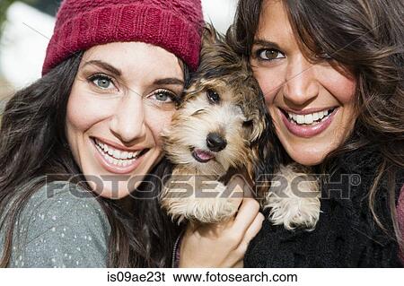 Friends holding pet dog for photograph View Large Photo Image Stock Photograph - Friends holding pet dog for photograph. Fotosearch