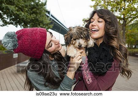 Stock Photograph - Friends holding pet dog for photograph. Fotosearch
