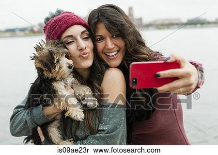 Friends holding pet dog for photograph View Large Photo Image Stock Photography - Friends holding pet dog for photograph. Fotosearch