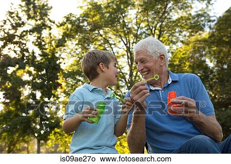 Picture - Grandfather and grandson blowing bubbles. Fotosearch
