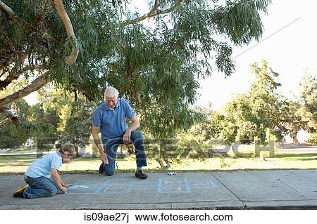 Stock Image - Grandfather and grandson drawing hopscotch. Fotosearch