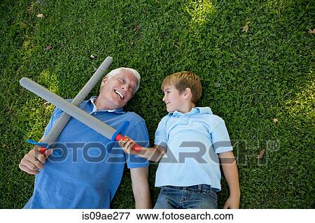 Grandfather and grandson lying on grass with toy swords View Large Photo Image Stock Photo - Grandfather and grandson lying on grass with toy swords. Fotosearch