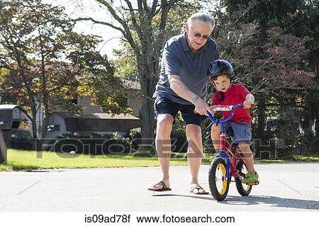 Grandfather encouraging young boy to ride bicycle View Large Photo Image Stock Image - Grandfather encouraging young boy to ride bicycle. Fotosearch