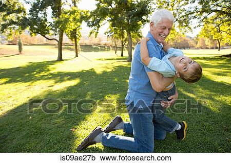 Grandfather kneeling on grass hugging grandson View Large Photo Image Stock Image - Grandfather kneeling on grass hugging grandson. Fotosearch