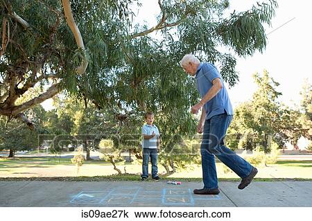 Stock Image - Grandfather on hopscotch, boy watching. Fotosearch