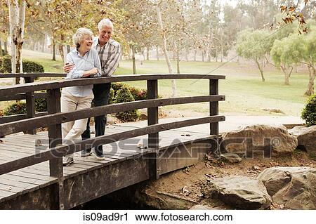 Husband and wife chatting lovingly on bridge in the park View Large Photo Image Stock Image - Husband and wife chatting lovingly on bridge in the park. Fotosearch