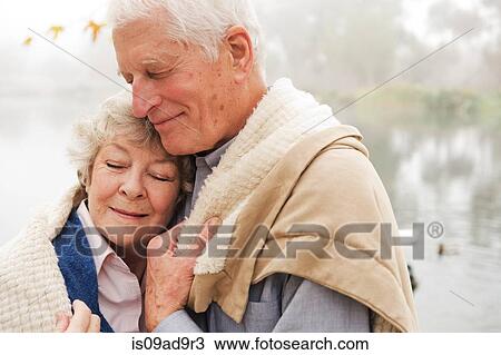 Stock Image - Husband and wife hugging with eyes closed. Fotosearch