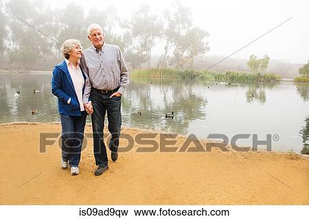 Stock Photo - Husband and wife strolling by the lake. Fotosearch