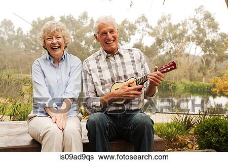 Husband playing the ukelele with wife by lake View Large Photo Image Stock Photograph - Husband playing the ukelele with wife by lake. Fotosearch