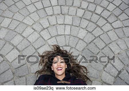 Mid adult woman lying on pavement, looking at camera View Large Photo Image Stock Photography - Mid adult woman lying on pavement, looking at camera. Fotosearch