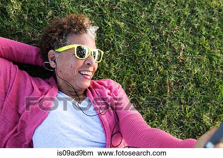Portrait of senior woman lying on grass wearing sunglasses View Large Photo Image Picture - Portrait of senior woman lying on grass wearing sunglasses. Fotosearch