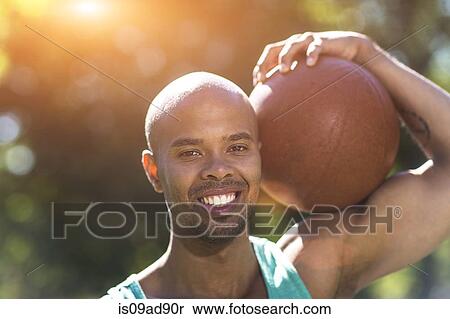 Stock Photography - Portrait of young man holding basketball. Fotosearch