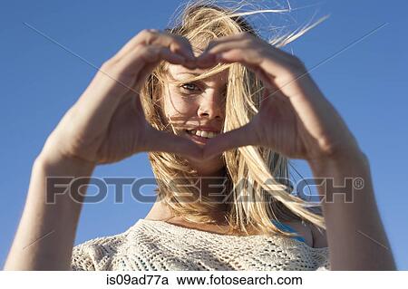 Stock Image - Portrait of young woman making heart sign, Breezy Point, Queens, New York, USA. Fotosearch