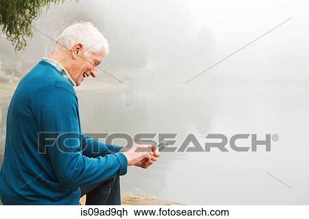 Senior man smiling at text on mobile phone View Large Photo Image Stock Image - Senior man smiling at text on mobile phone. Fotosearch