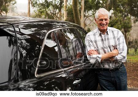 Senior man standing against black vehicle View Large Photo Image Picture - Senior man standing against black vehicle. Fotosearch