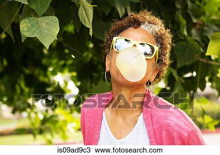 Stock Image - Senior woman blowing bubble gum. Fotosearch