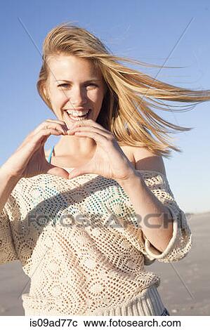 Stock Image - Smiling woman making heart sign with hands, Breezy Point, Queens, New York, USA. Fotosearch