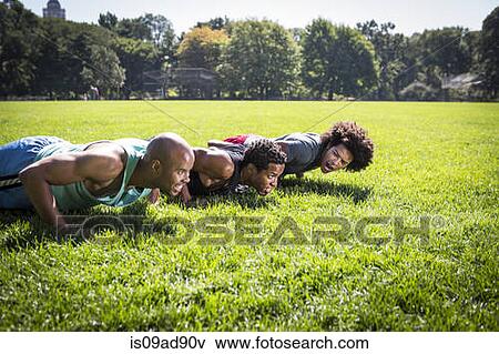 Stock Photo - Three young men doing push ups in park. Fotosearch