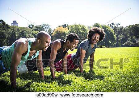 Stock Photo - Three young men doing push ups in park. Fotosearch