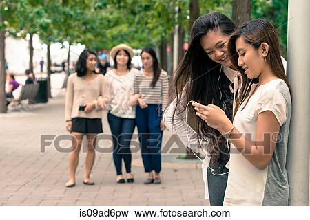 Women looking at technology, friends approaching View Large Photo Image Stock Photo - Women looking at technology, friends approaching. Fotosearch