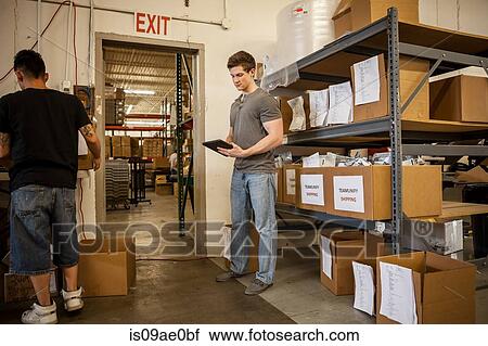 Workers in warehouse looking at paperwork View Large Photo Image Stock Image - Workers in warehouse looking at paperwork. Fotosearch
