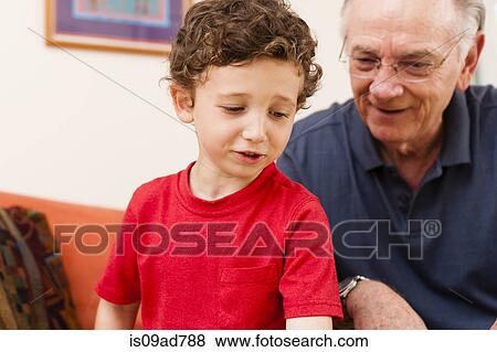 Stock Photo - Young boy and grandfather in sitting room. Fotosearch