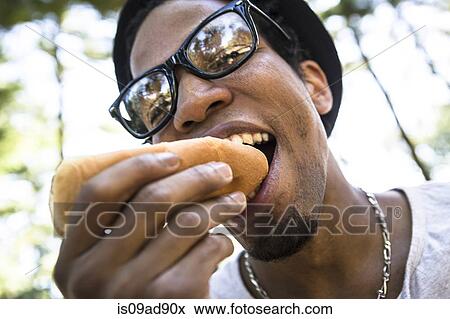 Stock Photo - Young man eating bread roll. Fotosearch