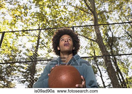 Stock Image - Young man holding basketball. Fotosearch