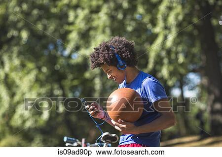 Stock Photography - Young man holding basketball with mp3 player. Fotosearch