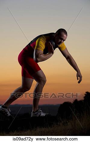 Young man preparing to throw shot put at sunset View Large Photo Image Stock Photo - Young man preparing to throw shot put at sunset. Fotosearch
