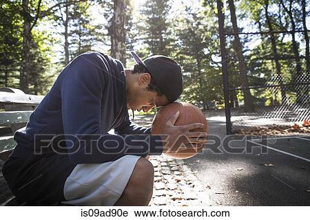 Young man sitting on park bench resting head on basketball View Large Photo Image Stock Image - Young man sitting on park bench resting head on basketball. Fotosearch
