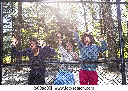 Young men by wire fence in park View Large Photo Image Stock Image - Young men by wire fence in park. Fotosearch