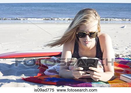 Young woman looking at digital tablet on beach, Breezy Point, Queens, New York, USA View Large Photo Image Stock Photography - Young woman looking at digital tablet on beach, Breezy Point, Queens, New York, USA. Fotosearch
