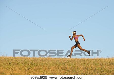 Stock Photography - Young woman running across field. Fotosearch