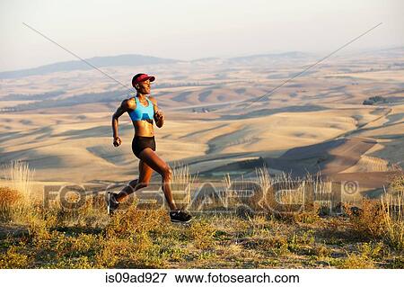 Stock Photo - Young woman running on hill, Bainbridge Island, Washington State, USA. Fotosearch
