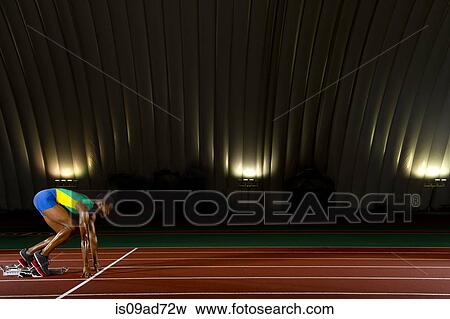 Young woman sprinting on starting blocks in stadium View Large Photo Image Stock Photo - Young woman sprinting on starting blocks in stadium. Fotosearch