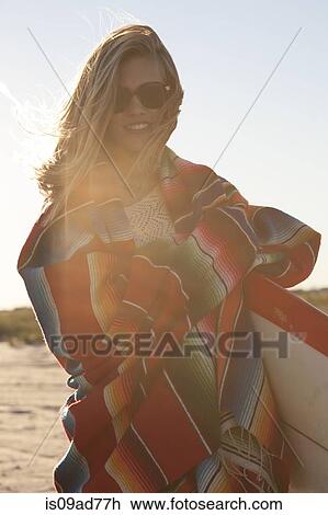 Stock Image - Young woman wrapped in blanket, Breezy Point, Queens, New York, USA. Fotosearch