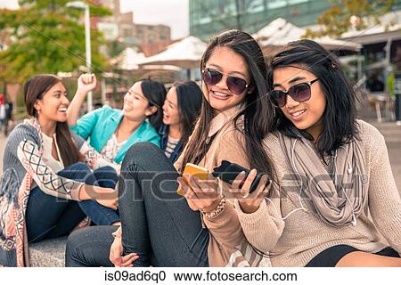 Stock Image - Young women looking at smartphones. Fotosearch