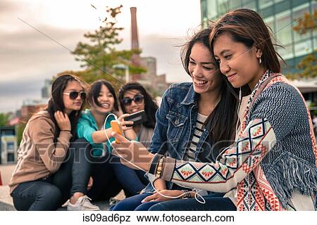 Young women taking self portrait photographs using smartphones View Large Photo Image Stock Photo - Young women taking self portrait photographs using smartphones. Fotosearch