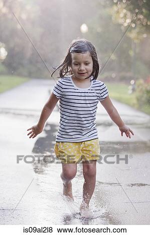 Stock Photo - Barefoot girl running through puddles on rainy street. Fotosearch