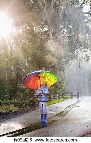 Stock Photograph - Boy carrying umbrella and looking up on street. Fotosearch