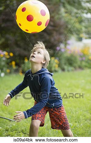 Stock Image - Boy playing with ball game in garden. Fotosearch