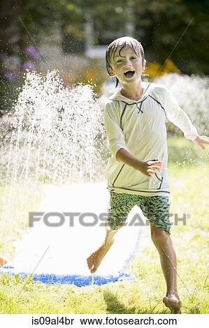 Stock Photography - Boy playing with garden sprinkler. Fotosearch